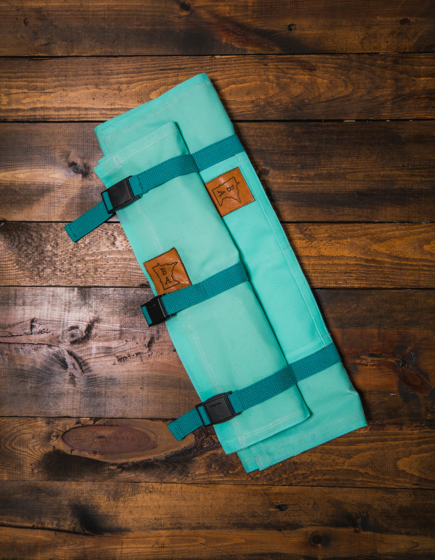 Electric blue Main Squeeze and Side Hustle matching set displayed on a wooden surface. The cotton knife rolls were handcrafted in Minnesota by Craftmade Aprons. 