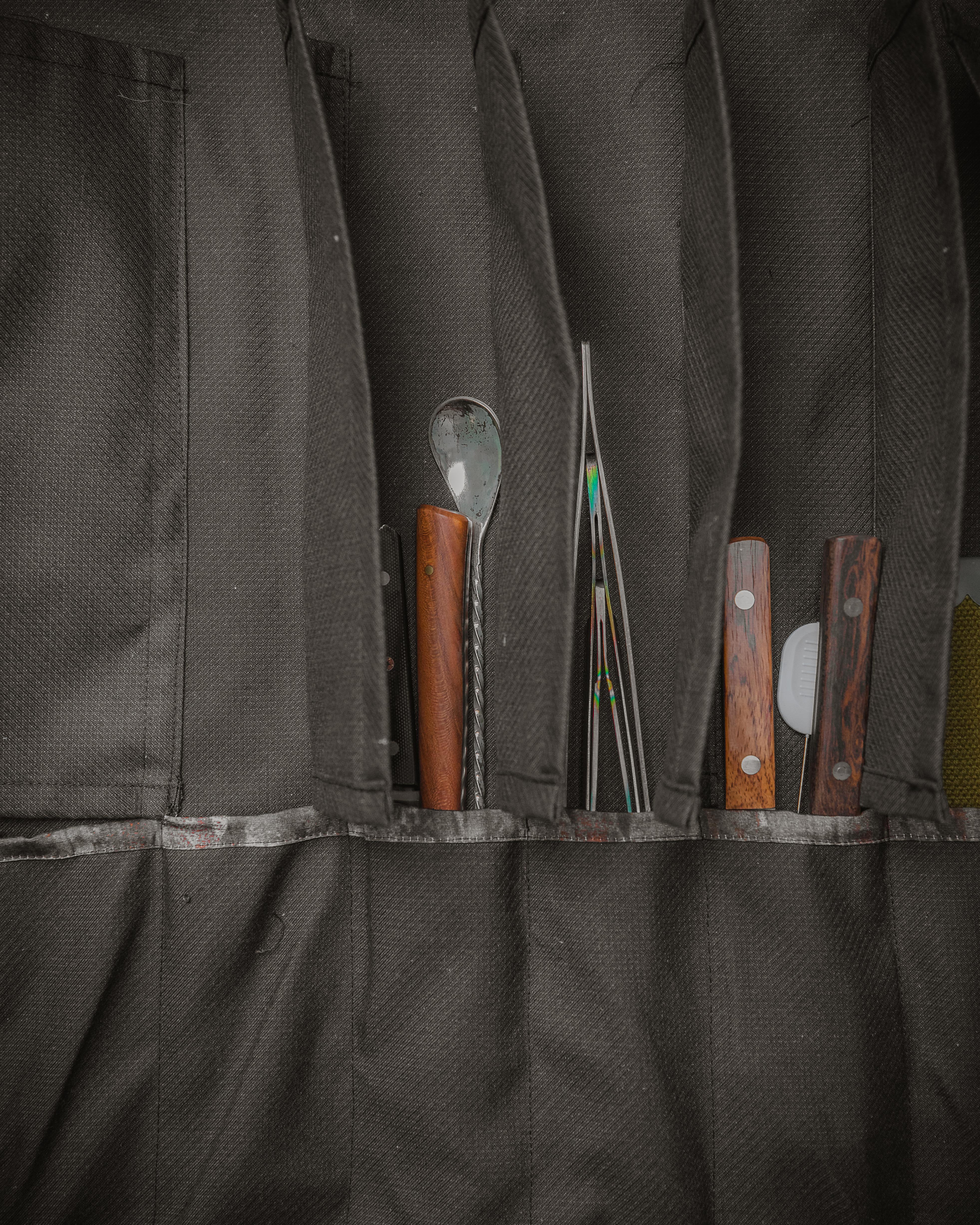 Product shot of the Main Squeeze interior with many knives and other utensils in its pockets. Designed in Minnesota by Craftmade Aprons.