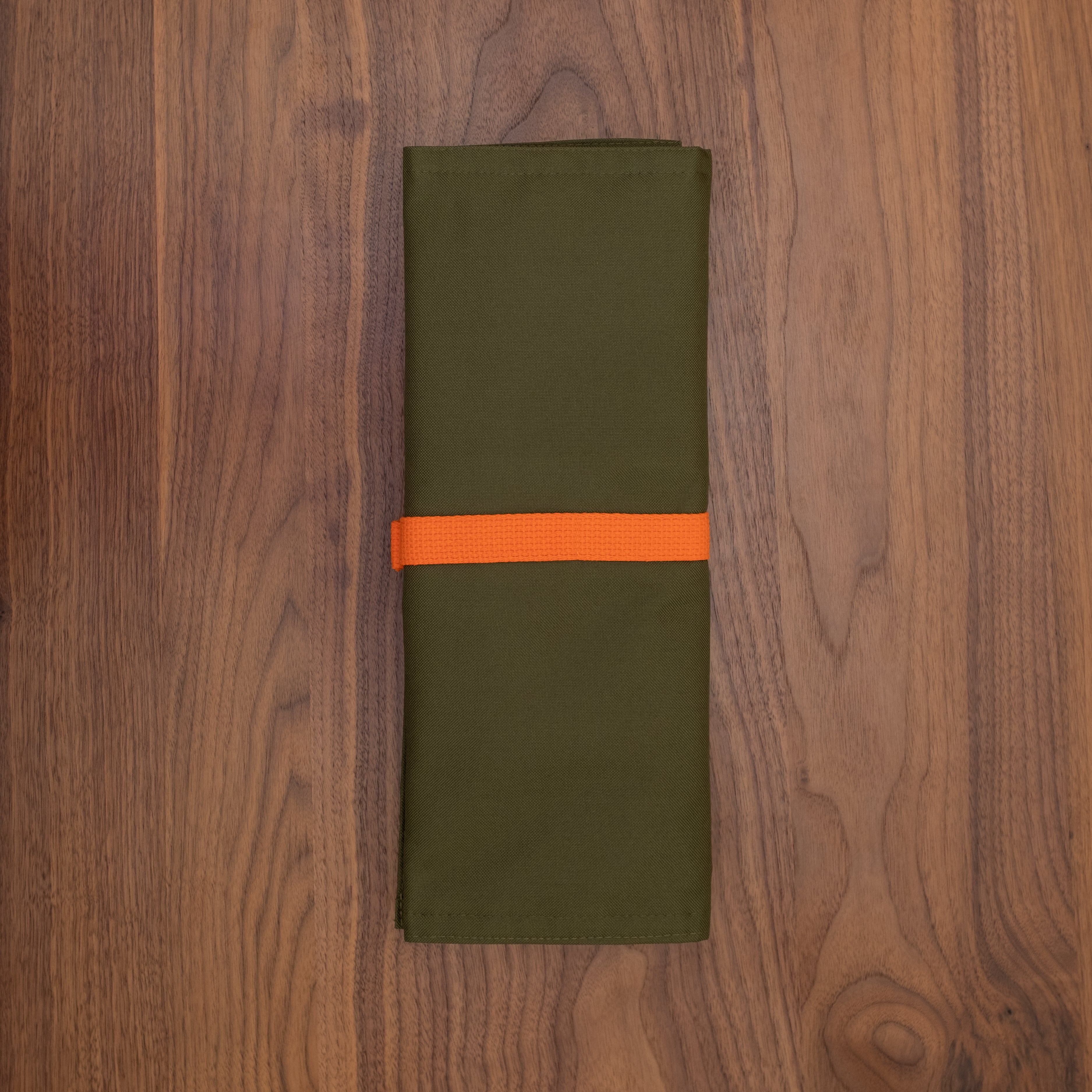 The back of the Ottertex Edition olive/Orange Side Hustle knife roll is shown. Handcrafted in Minnesota by Craftmade Aprons.