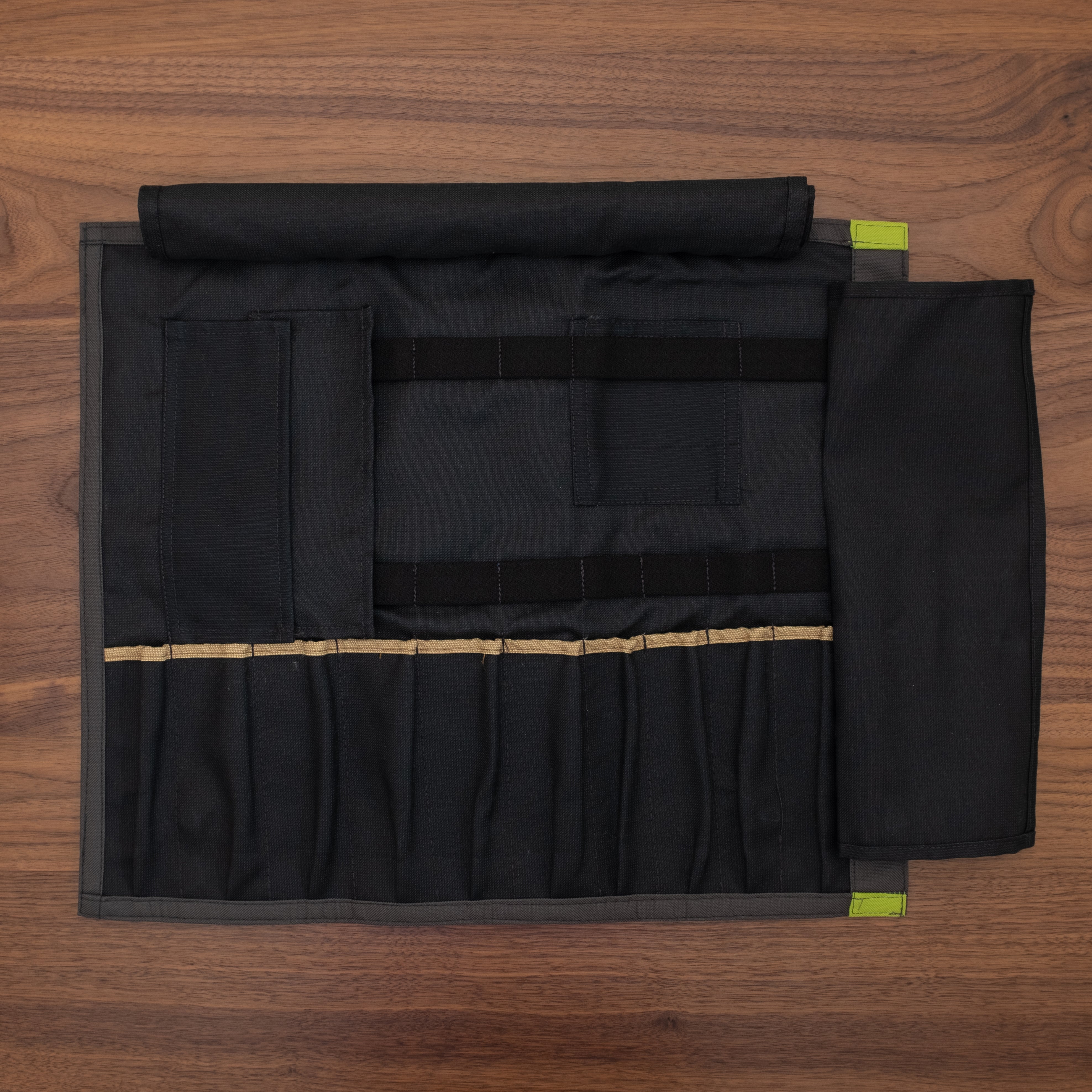 Black interior of the Ottertex Edition/Totally Rad Side Hustle knife  roll laid out flat on a wooden surface. The interior is made of a 50-50 Kevlar/Nomex blend for long lasting protection. Design by Craftmade Aprons in Minnesota.