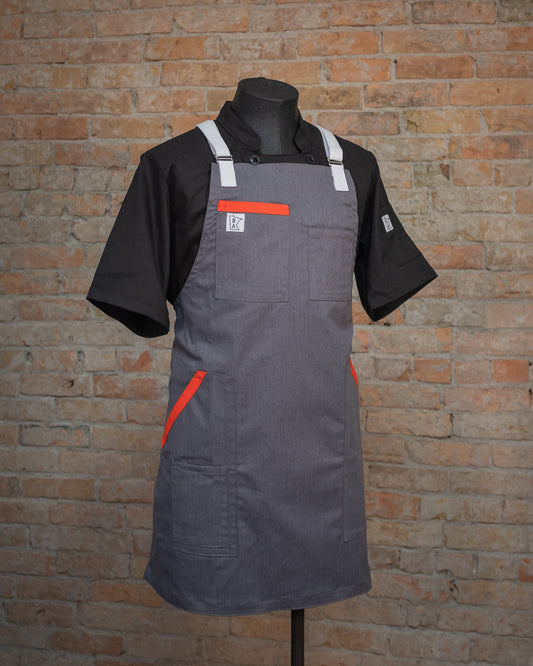 The cotton apron design Dreamsicle displayed on a mannequin over a black chef coat. Both the chef coat and apron were designed and produced by Craftmade Aprons, Minnesota. 