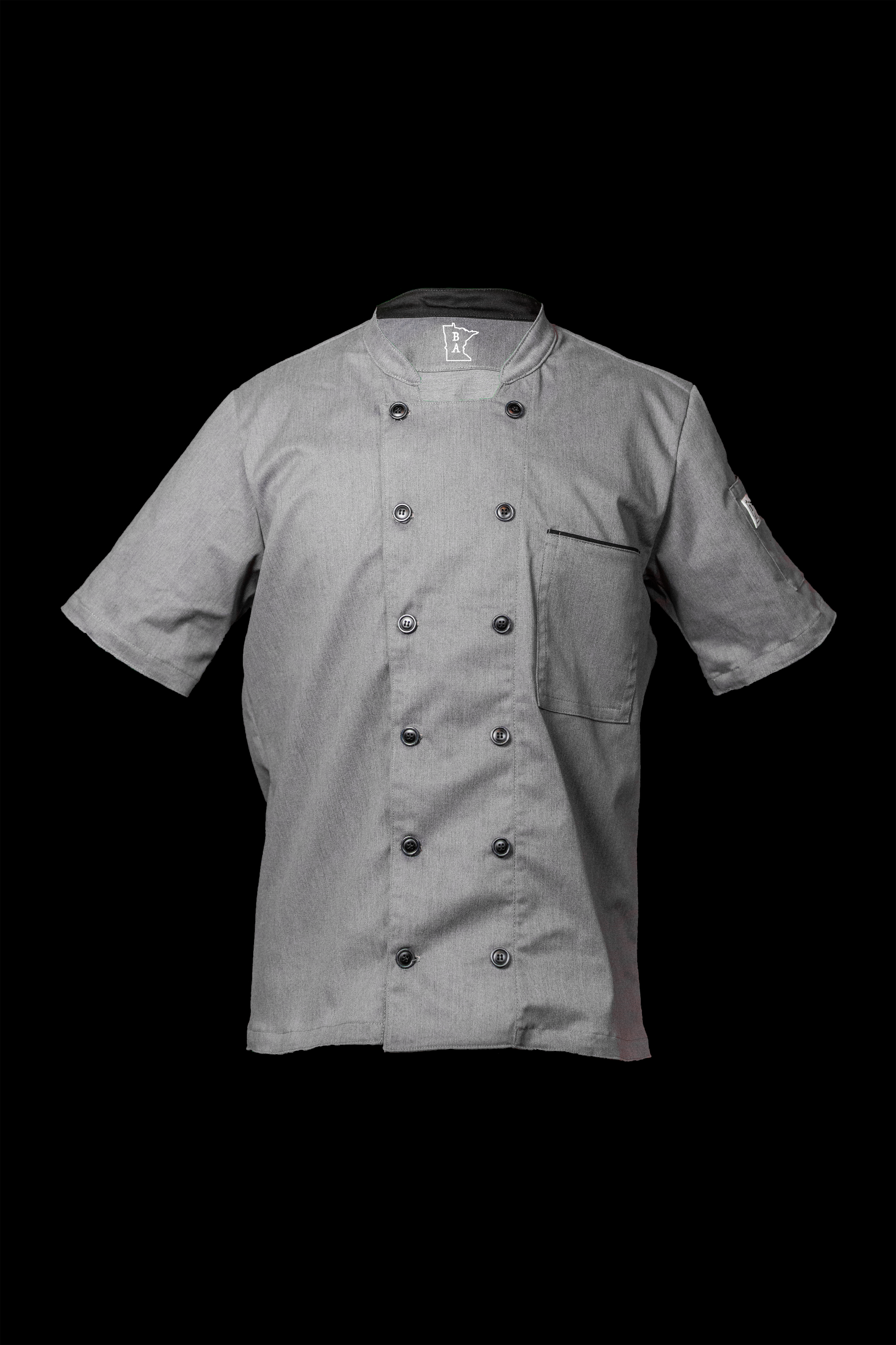 Men's heather gray chef coat with black trim. The material is Salerno Stretch Twill, made for high performance. The chef coat has one upper breast pocket and a left arm duel slotted sleeve pocket with 12 buttons running down the center. Designed by Craftmade Aprons in Minnesota.