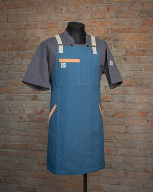 The cotton duck cloth design Miami Nice displayed on a mannequin over a gray chef coat. Both the chef coat and the apron were designed and produced by Craftmade Aprons, Minnesota.