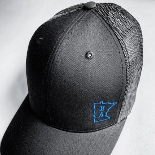 Charcoal gray trucker cap with blue Craftmade logo with a white background.  Supported by Project Black and Blue. 