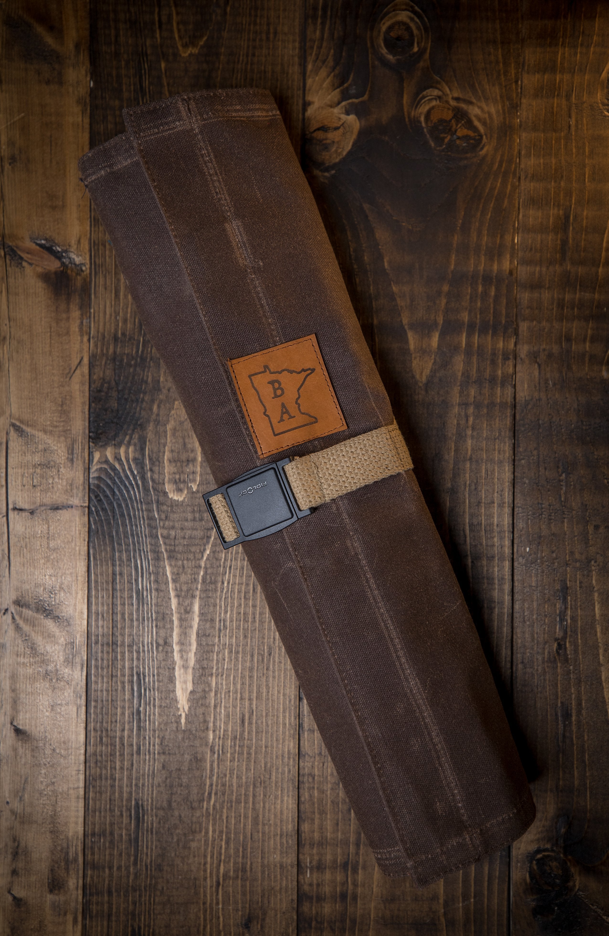 Long lasting brown cotton knife roll with tex-wax protection shown on a wooden surface. The Side Hustle knife roll was manufactured in Minnesota by Craftmade Aprons.