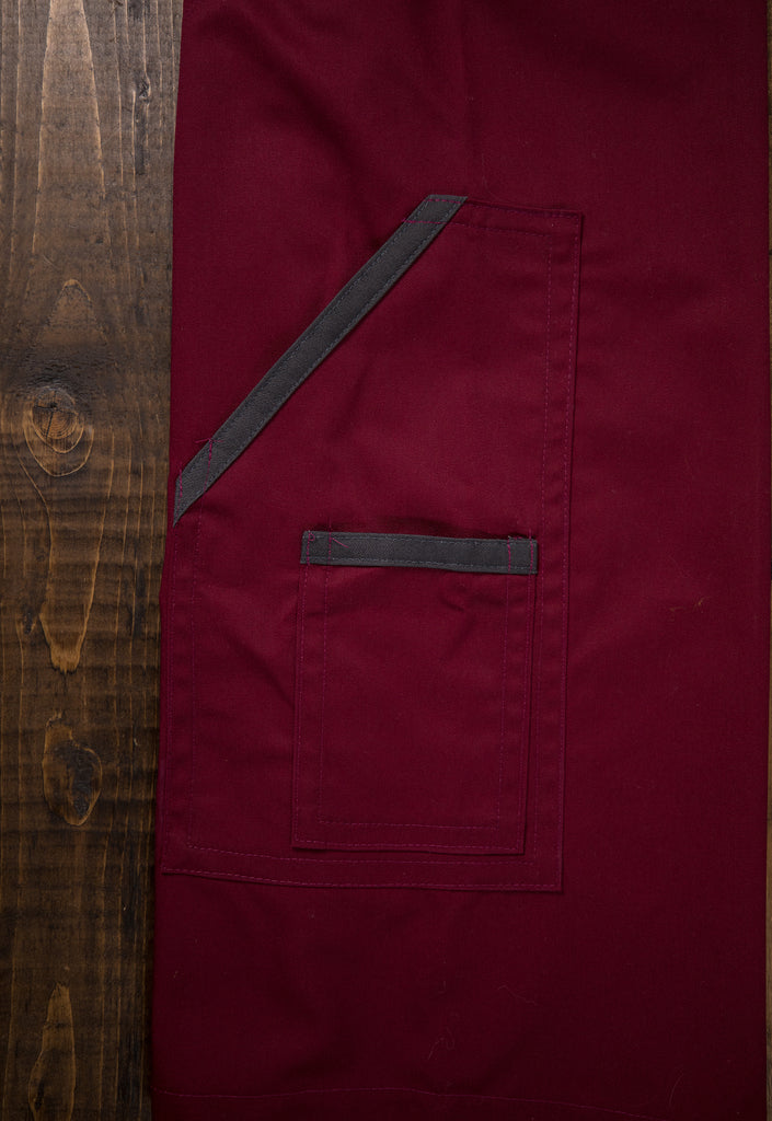 Product shot of apron design Excalibur, showing the dark gray trim on the merlot pockets close up. Designed and produced by Craftmade Aprons, Minnesota.